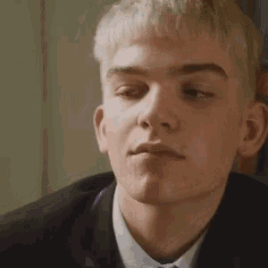 a close up of a young man in a suit and tie making a funny face .