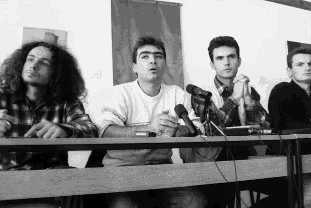 a group of men sitting at a table with microphones in front of them