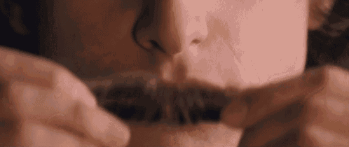 a close up of a person 's mouth with a mustache and smoke coming out of it .