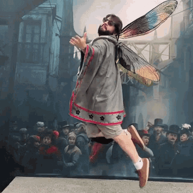 a man in a fairy costume is flying in front of a crowd of people