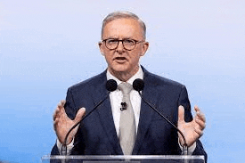 a man in a suit and tie is speaking into two microphones .