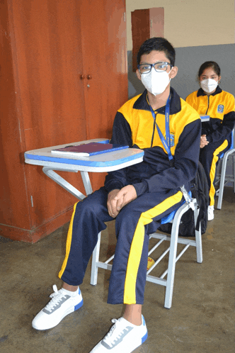 a boy wearing a mask sits in a classroom