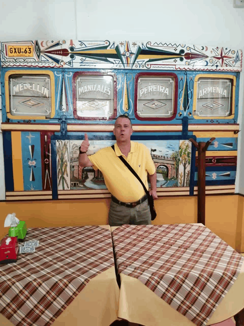 a man stands in front of a colorful wall that says medellin and pereira