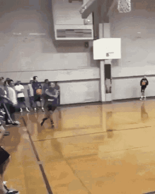 a basketball game is being played in a gym with a player wearing a shirt that says ' basketball '