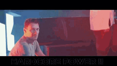 a man is sitting at a table in a dark room with the words hardcore power written on the bottom .