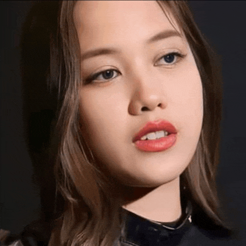 a close up of a woman 's face with red lips and a black background .