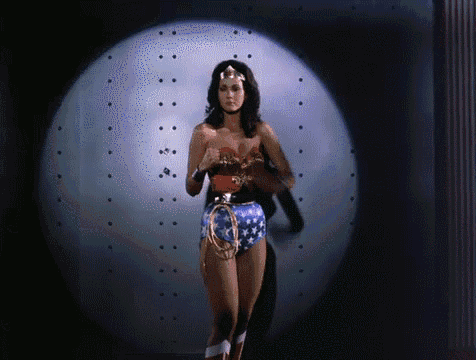 a woman in a wonder woman costume stands in front of a spotlight