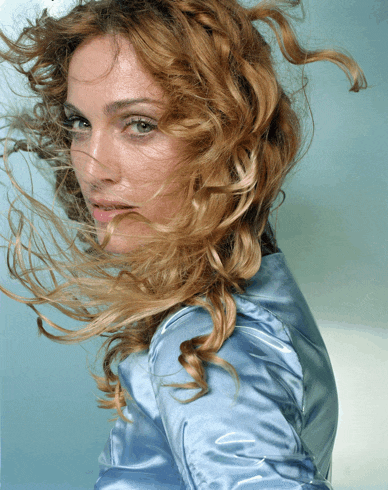 a woman with her hair blowing in the wind is wearing a blue shirt