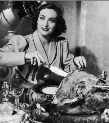 a woman is cutting a large turkey with a knife and fork