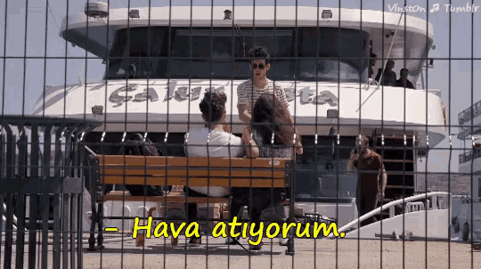 a group of people sitting on a bench in front of a boat with the words hava atiyorum written on it