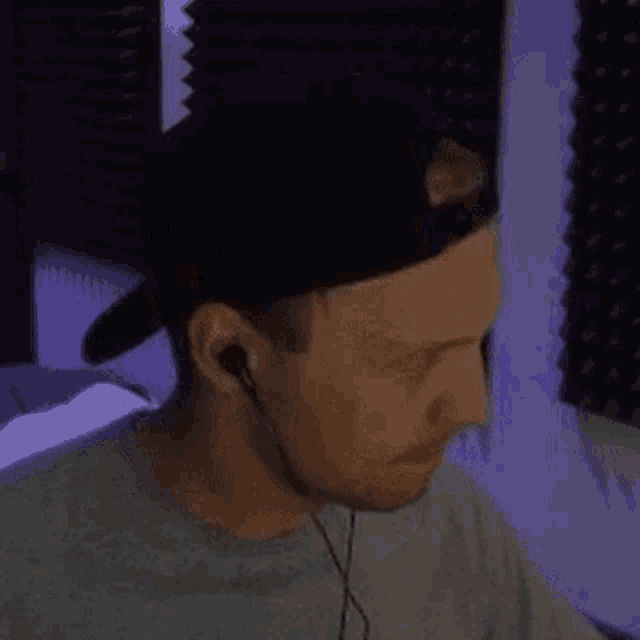 a man wearing a baseball cap and earbuds looks down
