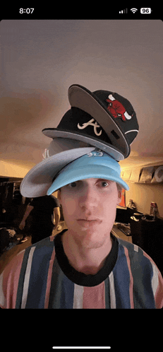 a man with a stack of hats on his head and the time 8:17