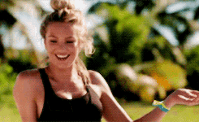 a woman in a black tank top with a bun on her hair is smiling