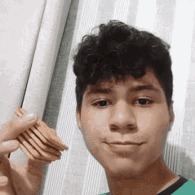 a young man in a green shirt is holding a stack of cookies .