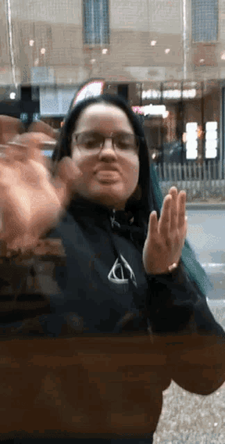 a woman wearing glasses and a black sweatshirt with a triangle on it