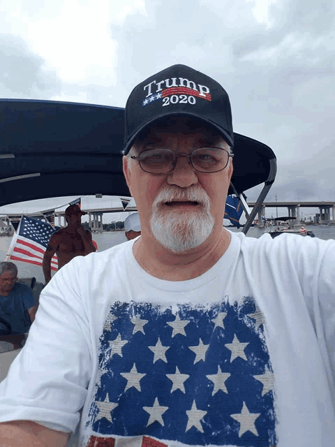 a man wearing a trump 2020 hat and a white shirt