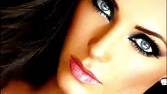 a close up of a woman 's face with smokey eyes and pink lips .