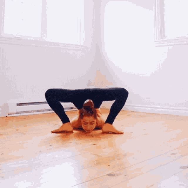a woman is doing a yoga pose on a wood floor .