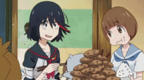 two anime girls are standing next to each other with a pile of cookies in front of them