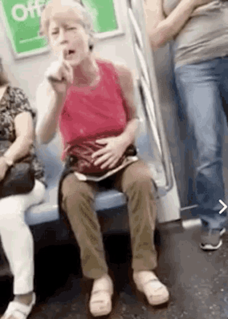 a woman in a red tank top is sitting on a train with a sign that says off