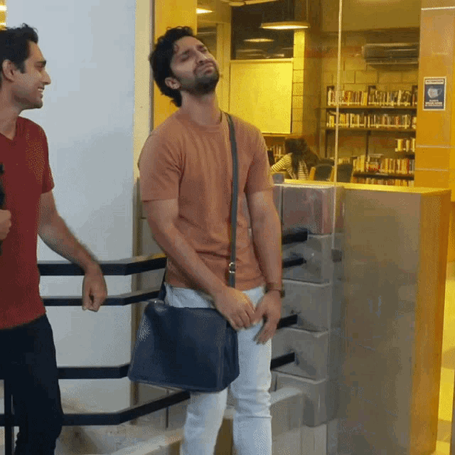 two men standing next to each other in a library with a sign on the wall that says ' no smoking '