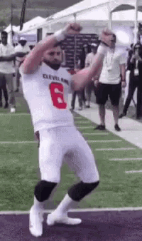 a football player is dancing on the field while wearing a white jersey with the number 6 on it .