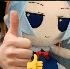 a stuffed animal with blue eyes is giving a thumbs up