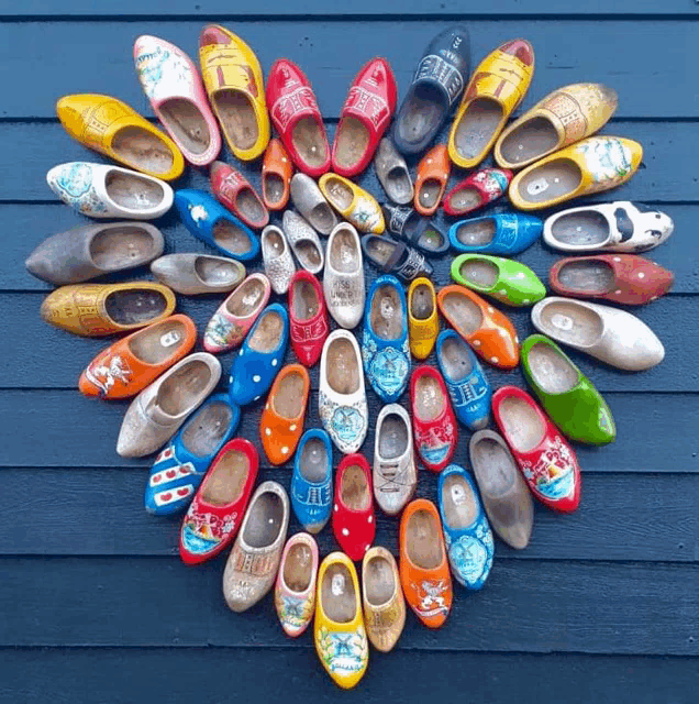 a bunch of clogs are arranged in a heart shape on a blue surface