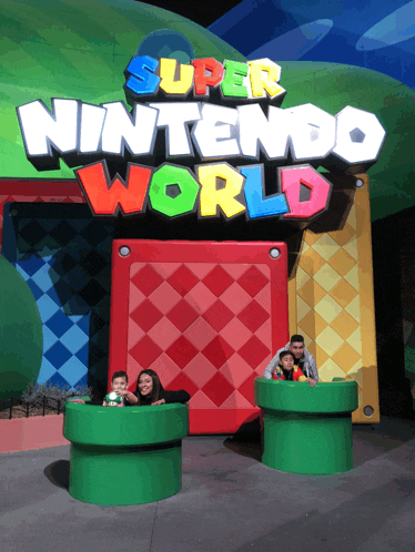 a group of people pose in front of the super nintendo world