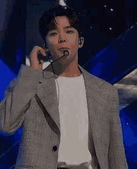 a man wearing a suit and a white shirt is singing into a microphone .