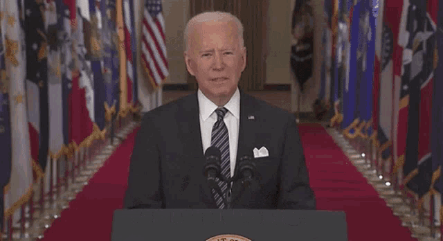 a man in a suit and tie is standing in front of a podium with the words and it must stop written below him .