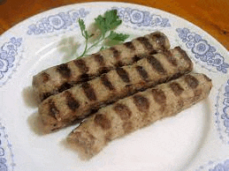 three grilled sausages on a white plate with parsley .