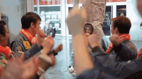 a group of people applauding a man wearing glasses and a yellow patch that says vodafone on it
