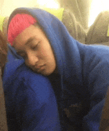 a person with pink hair is wearing a blue hoodie and sleeping