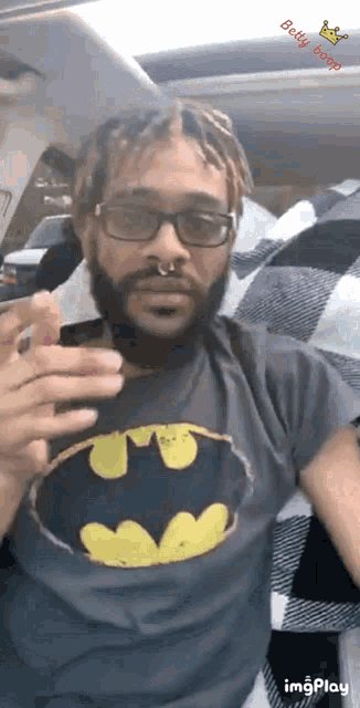 a man wearing a batman t-shirt is sitting in the back seat of a car