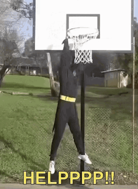 a man in a batman costume is jumping over a basketball hoop with the words helpppp ! below him .