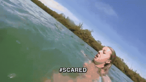 a woman is swimming in a body of water and the words scared are visible .