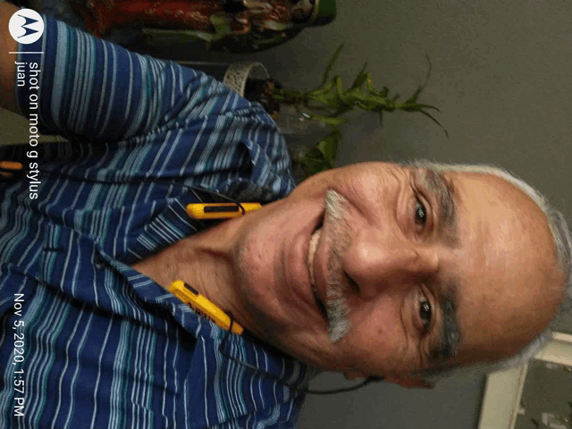 a man with a mustache is smiling in a photo taken by a motorola phone