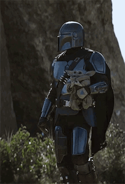 a man in armor is holding a baby on his back .