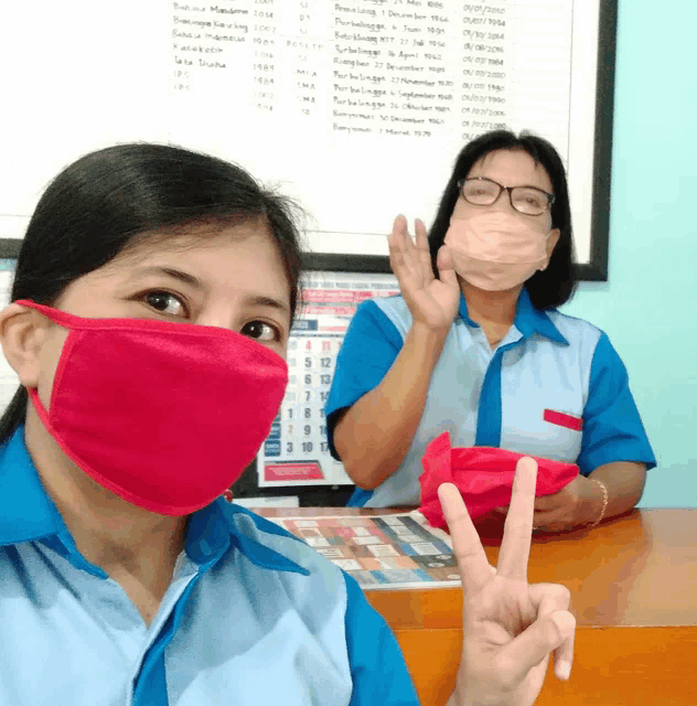 a woman wearing a red face mask giving a peace sign