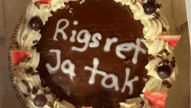 a chocolate cake with the words rigsrer ja tak written in white