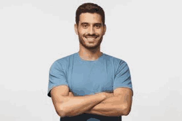 the man is wearing a blue t-shirt and smiling with his arms crossed .