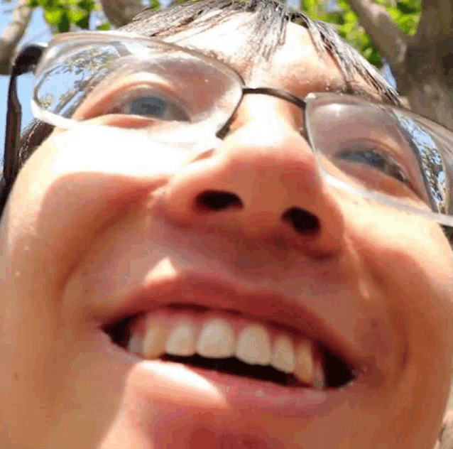 a close up of a person 's face wearing glasses and smiling