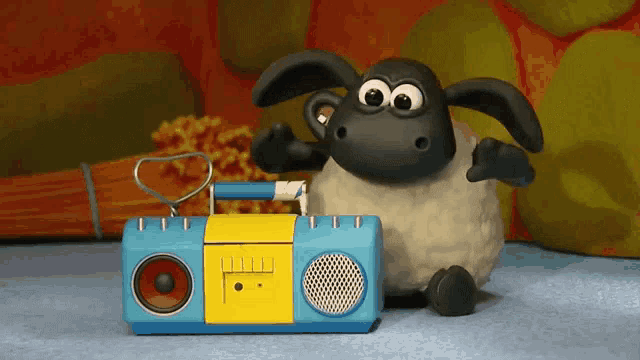 a cartoon sheep is sitting next to a blue and yellow radio