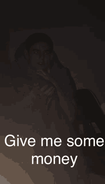 a man sits in a dark room with the words give me some money above him