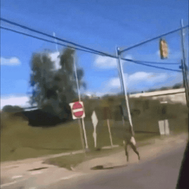 a person is walking down a street with a do not enter sign