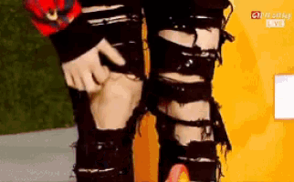 a person wearing a pair of black ripped jeans is standing in front of a sign that says cnn