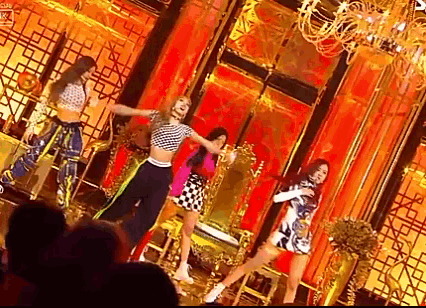 a group of women are dancing on a stage in a room .