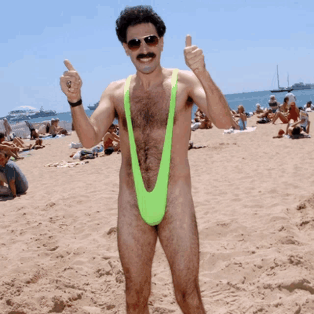 a man in a green slingshot giving a thumbs up on the beach