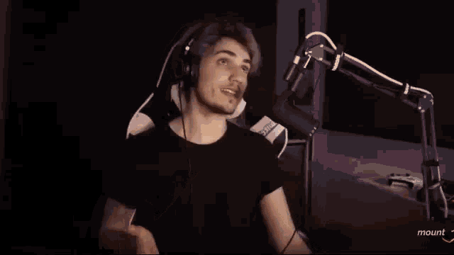 a man wearing headphones is pointing at a microphone that says mount on the bottom right